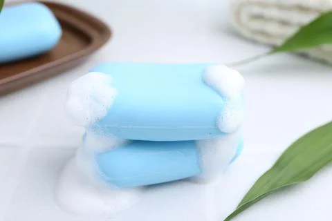 Soap bars with foam on white table, closeup Stockfoto's