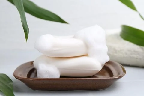 Soap bars with foam on white table, closeup 스톡 사진