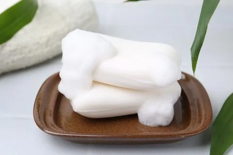 Soap bars with foam on white table, closeup Stockfoto's