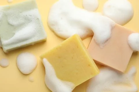 Soap bars with foam on yellow background, flat lay Stock Photos