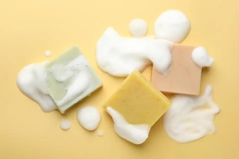 Soap bars with foam on yellow background, flat lay Stock Photos