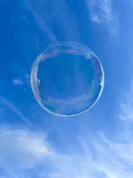 Soap bubble against a blue cloudy sky. Stock Photos