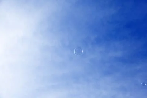 A soap bubble against a blue sky with thin clouds Stock Photos