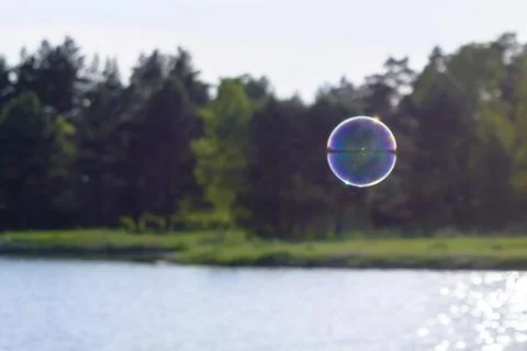 A soap bubble flies over the river Stock Photos