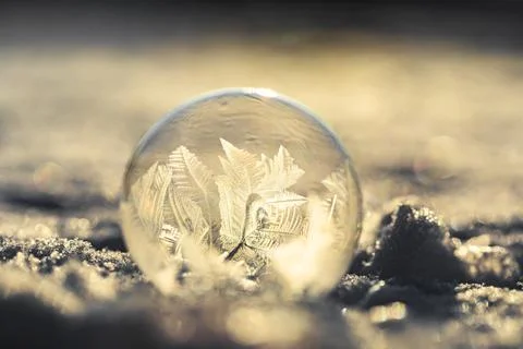 Soap bubble in the snow in winter. Ice patterns on the surface Stock Photos