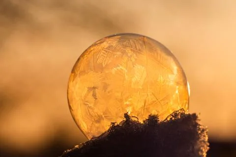 Soap bubble in the snow in winter. Ice patterns on the surface Stock Photos