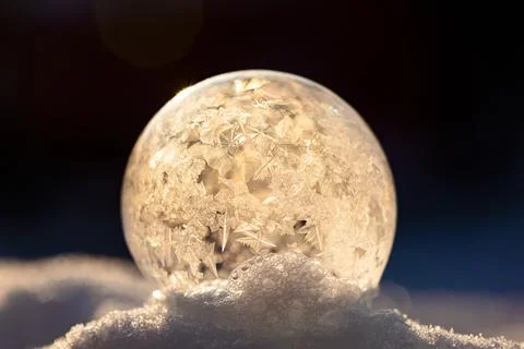 Soap bubble in the snow in winter. Ice patterns on the surface Stock Photos