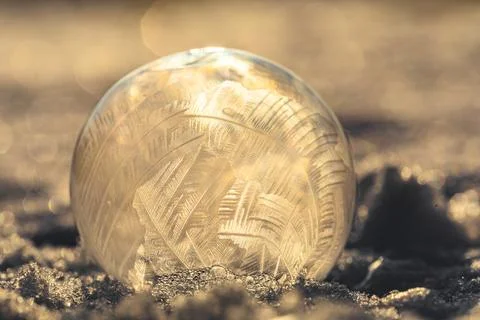 Soap bubble in the snow in winter. Ice patterns on the surface Stock Photos