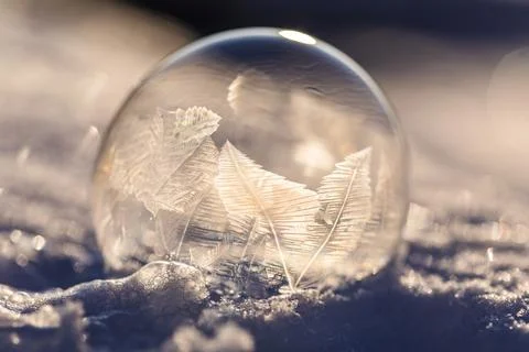 Soap bubble in the snow in winter. Ice patterns on the surface Stock Photos