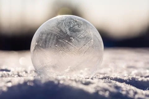 Soap bubble in the snow in winter. Ice patterns on the surface Stock Photos