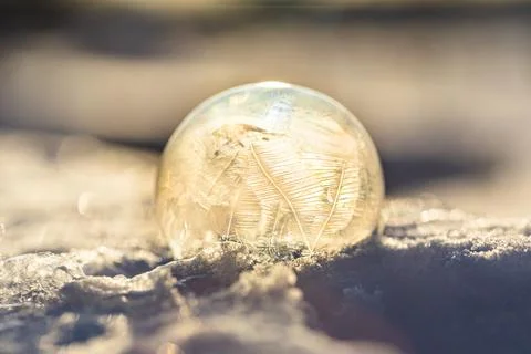 Soap bubble in the snow in winter. Ice patterns on the surface Stock Photos