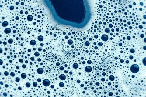 Soap bubbles on a background of blue water as a texture. Top view. Copy, em.. Stock Photos