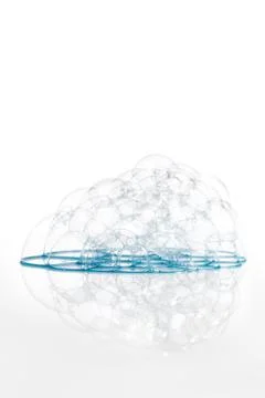 Soap bubbles with a blue tint on a flat surface with a reflection. Stock Photos