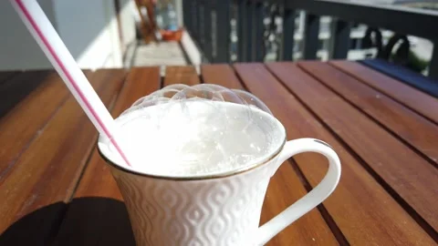 Soap bubbles in cup. Large straws inflate large soap bubbles from soap solution Stock Footage 134050238