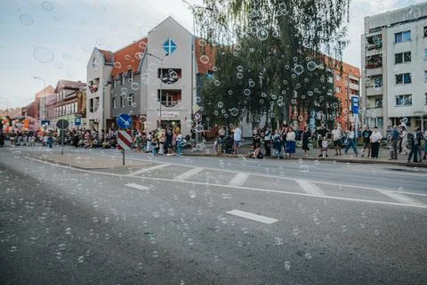 Soap bubbles drift down a sunlit city street during. Stock Photos