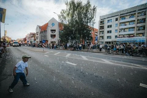 Soap bubbles drift down a sunlit city street during. Stock Photos