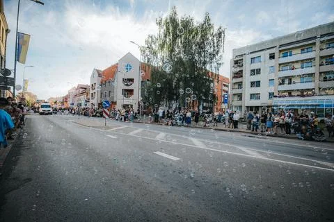 Soap bubbles drift down a sunlit city street during. Stock Photos