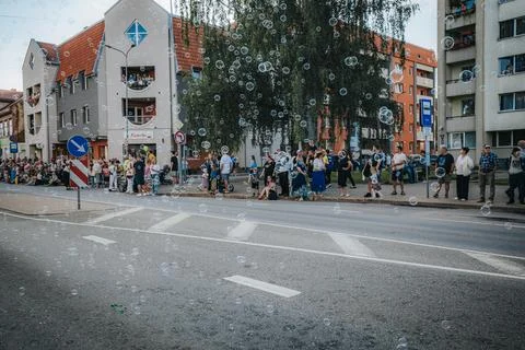 Soap bubbles drift down a sunlit city street during. Stock Photos