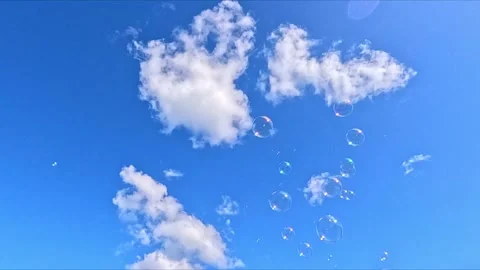 Soap bubbles drifting across blue sky with fluffy clouds Stock Footage 324785830