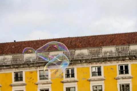 Soap bubbles drifting in front of yellow Lisbon building Stock Photos