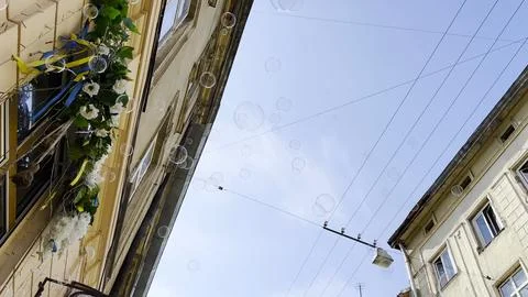 Soap bubbles float through sunlit city street with beautiful architecture i.. Stock Photos