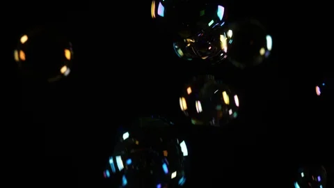 Soap bubbles floating in the air against an isolated black background Stock Footage 104981873