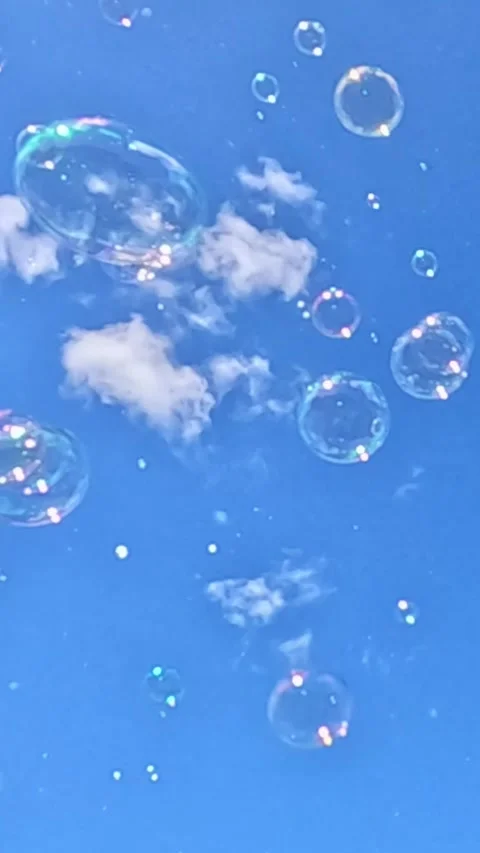 Soap bubbles floating in blue sky with white clouds Video stock 319915994