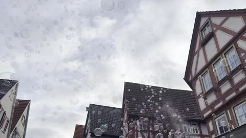 Soap bubbles floating through historic street in Besigheim with traditional Stock Footage 334579894