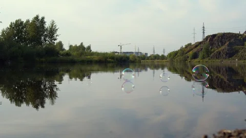 Soap bubbles fly over water of river Stock Footage 120686227
