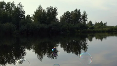 Soap bubbles fly over water of river Stock Footage 120686437