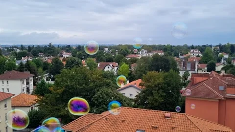 Soap bubbles flying slowly above beautiful red roofs in small green town en Stock-Footage 249943750