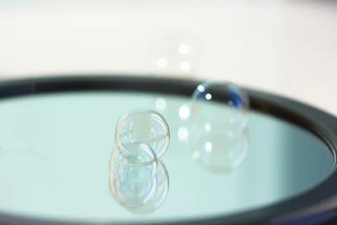 Soap bubbles on the surface of a round mirror. Reflection of soap bubbles. Stock Photos