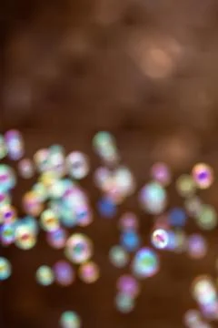 Soap bubbles on warm brown background. Vertical colorful bokeh with copy spac Stock Photos