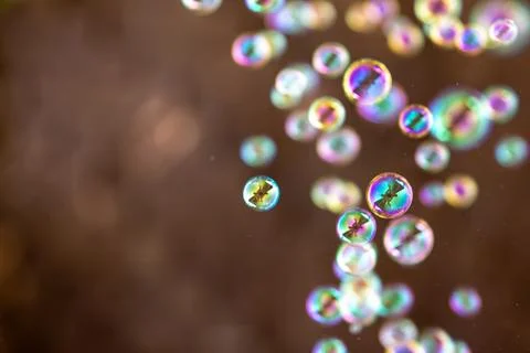 Soap bubbles on warm brown background. Colorful bokeh with wide copy space. Stock Photos