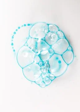 Soap bubbles on a white background from blue shower gel, top view. Stock Photos