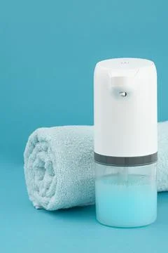 Soap dispenser automatic. In the background is a blue towel. Close-up. Blue b Stock Photos