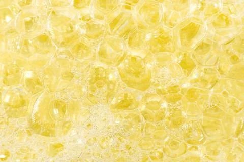 Soap foam close-up. Texture of soapy shampoo in yellow color Stock Photos
