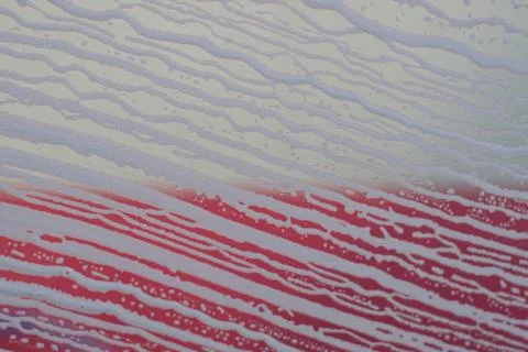 Soap foam pattern and bubbles on glass with red and white backgraund. Stock Photos