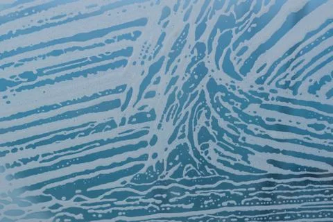 Soap foam pattern and bubbles on glass. Blue background. Stock Photos