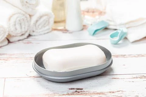 Soap on gray plastic soap dish with towels on white wooden table in bathroom 스톡 사진