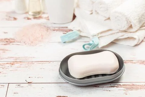 Soap on gray plastic soap dish with towels on white wooden table in bathroom Stock Photos