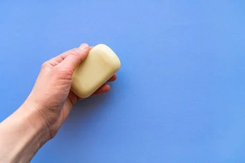 Soap for hand washing. Bar of soap in hand close-up on a blue background. Stock Photos