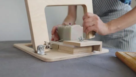 The soap maker cuts handmade flower soap on a wooden cutter Stock Footage 282154660