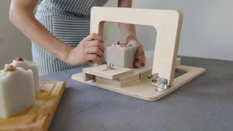The soap maker cuts handmade flower soap on a wooden cutter Stock Footage 282154699