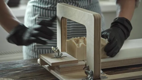 Soap maker cuts handmade honey soap with milk on a wooden cutter Stock Footage 278209583