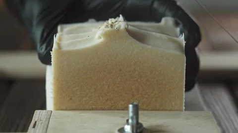 Soap maker cuts handmade honey soap with milk on a wooden cutter Stock Footage 278209606