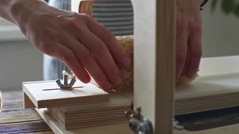 A soap maker cuts a round handmade honey soap on a wooden cutter Stock Footage 277873140