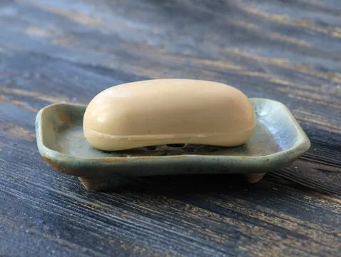 Soap placed on handmade ceramic soap dish on dark wooden surface Stock Photos