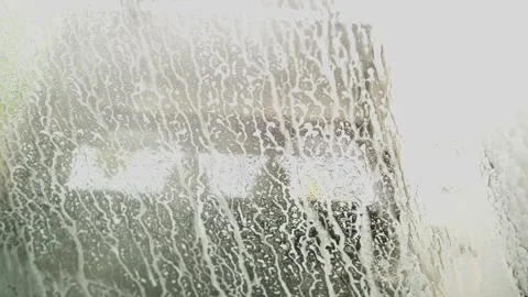Soapy foam with water droplets slowly sliding down a dirty windshield, cleaning Video stock 340230669