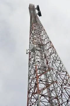 Soaring communication tower with multiple antennas reaching towards a cloud.. Stock Photos